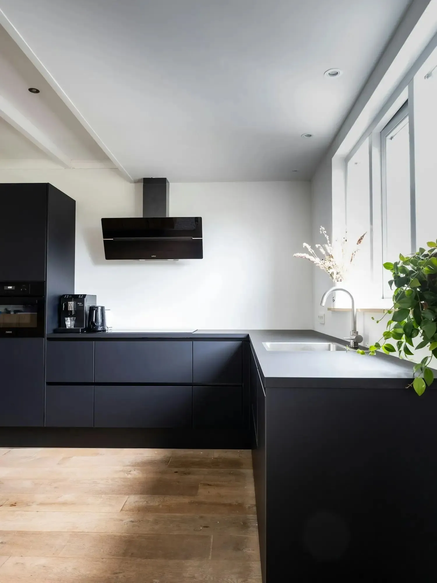Renovated kitchen with matte black cabinets and warm wood floors
